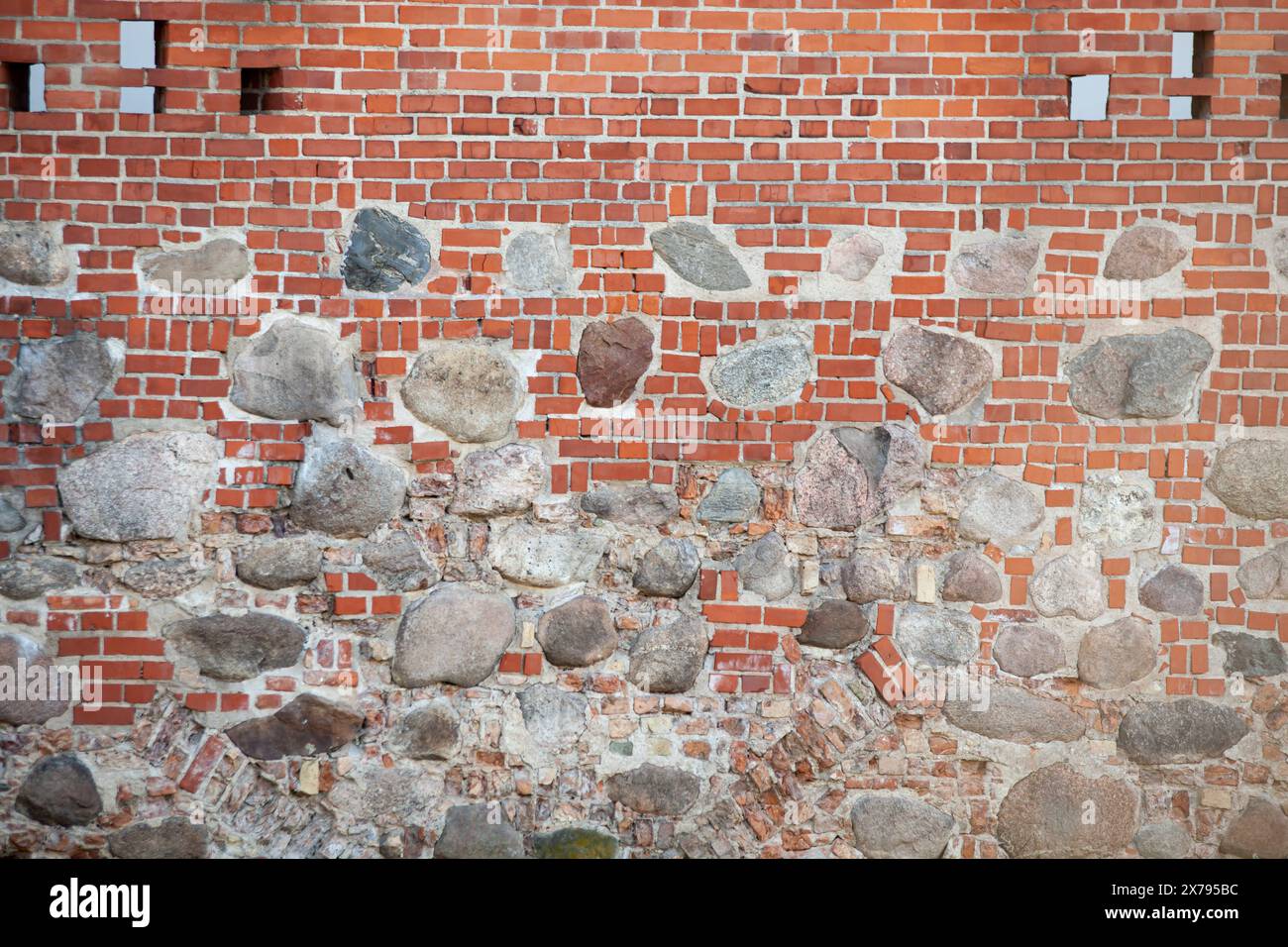 Alte rote Backsteinwand mit großen weißen Einsätzen und Fenstern. Die Textur des Ziegels. Hintergrund. Horizontal. Stockfoto