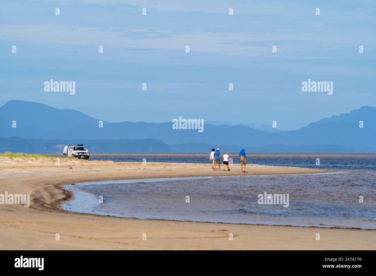 Das Fahrzeug parkte am Strand und vier Personen laufen am Sandstrand, Macquarie Heads, Westküste Tasmanien Stockfoto