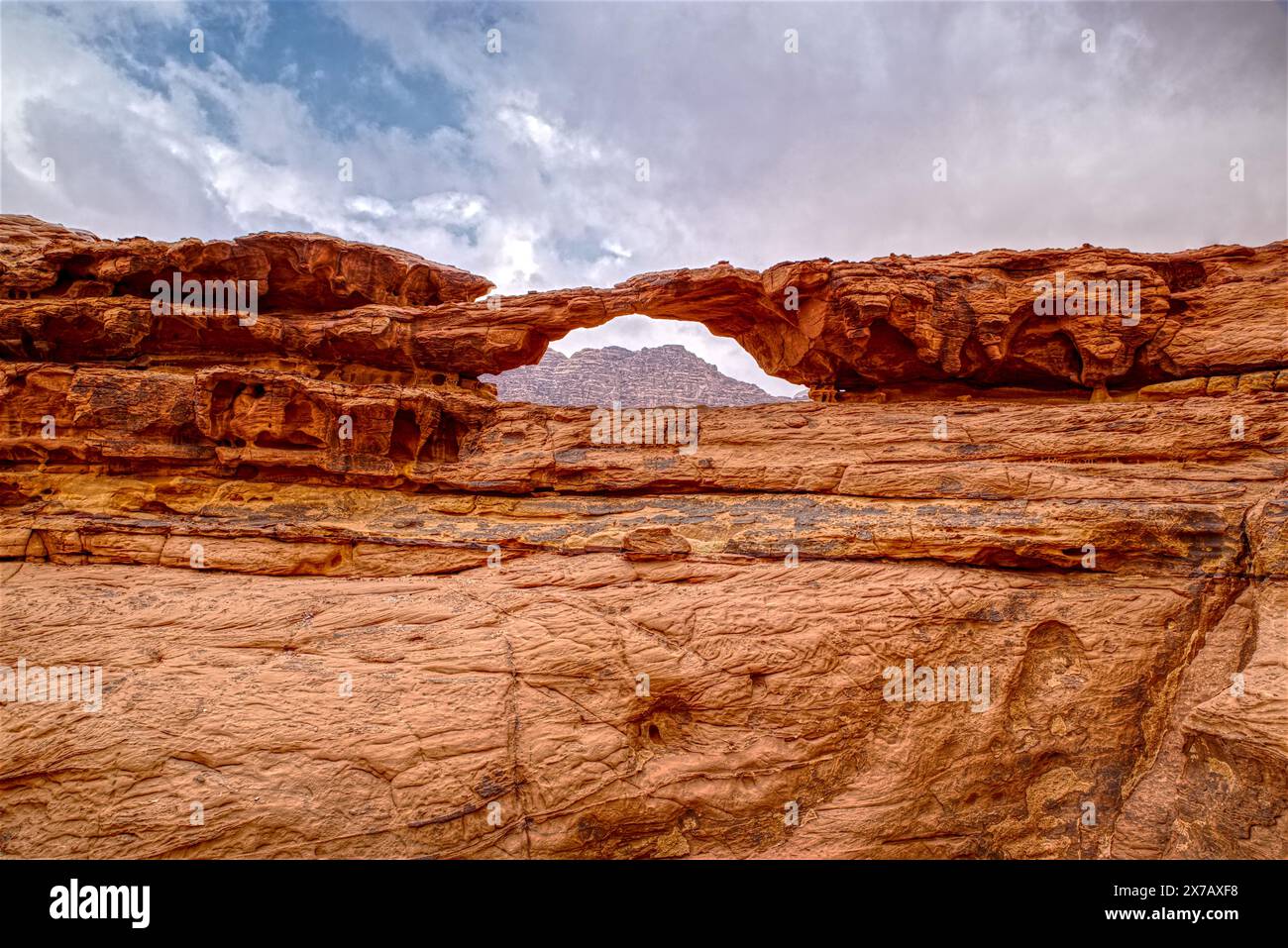 Jordanischer Wadi Rum Rocky Little Bridge mit wolkig stimmungsvollem Himmel im Hintergrund Stockfoto