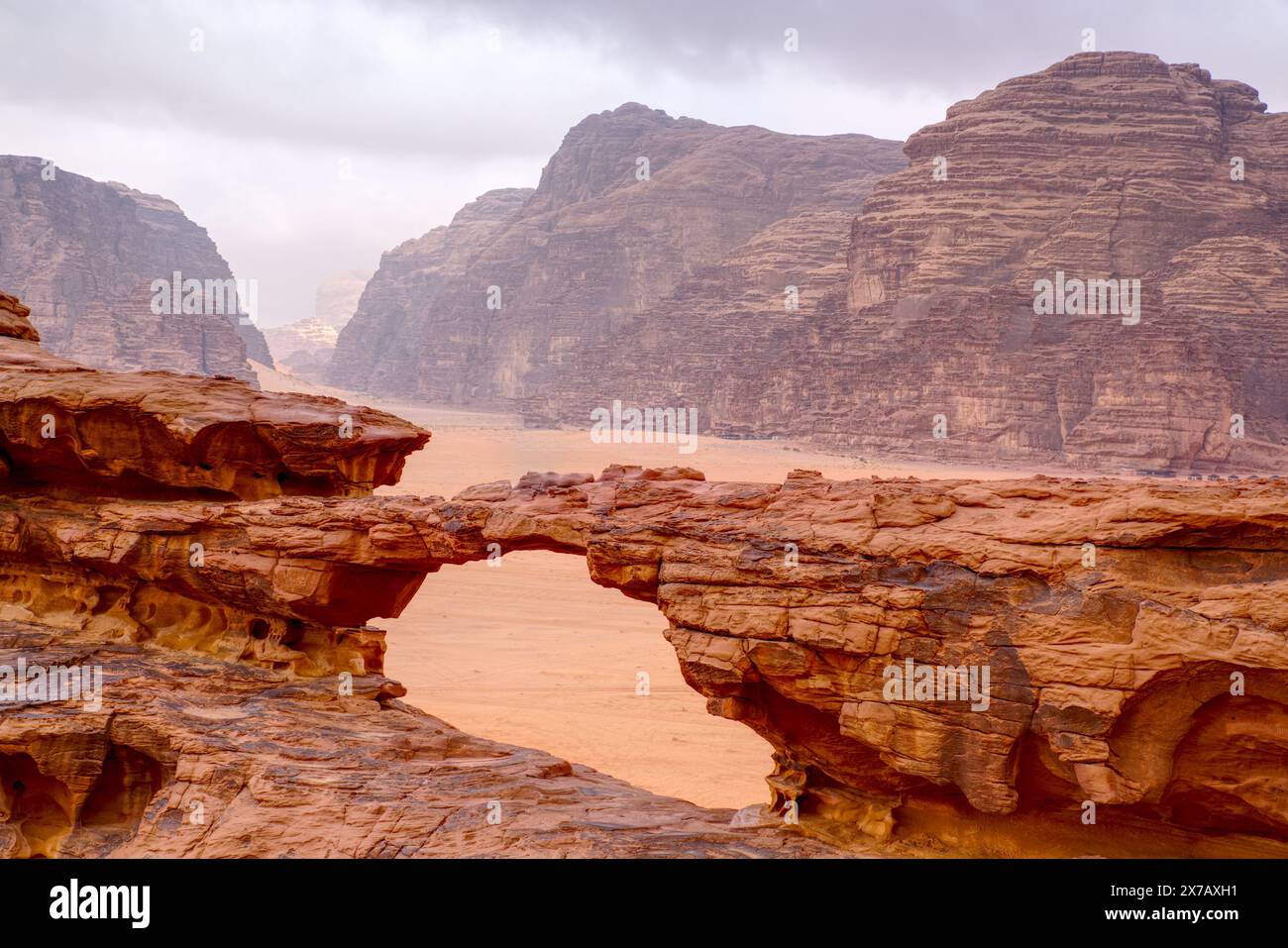 Jordanischer Wadi Rum Rocky Little Bridge mit wolkig stimmungsvollem Himmel im Hintergrund Stockfoto