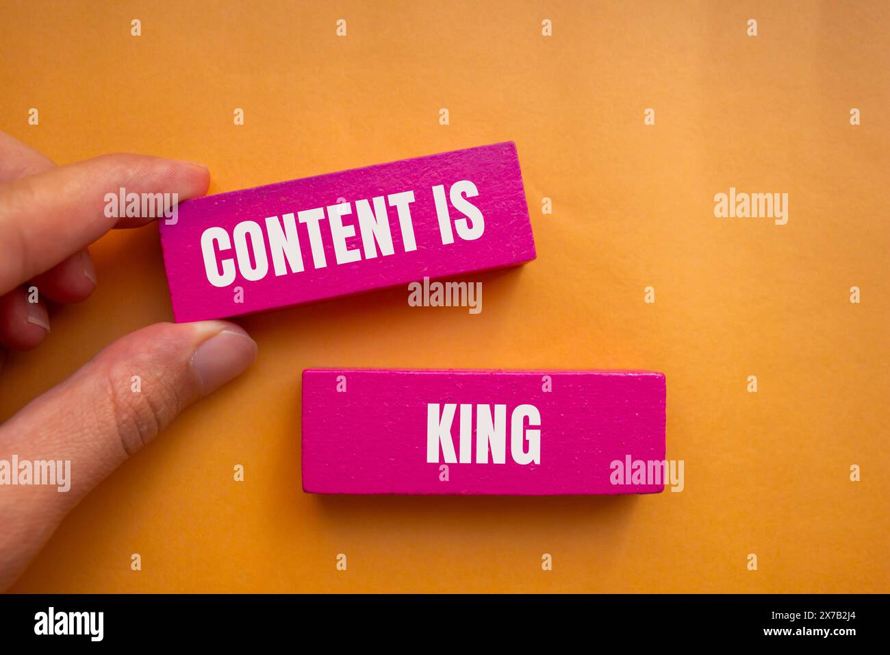 Inhalt ist Königsworte auf rosa Holzblöcken mit orangem Hintergrund. Konzeptueller Inhalt ist das Königssymbol. Kopierbereich. Stockfoto