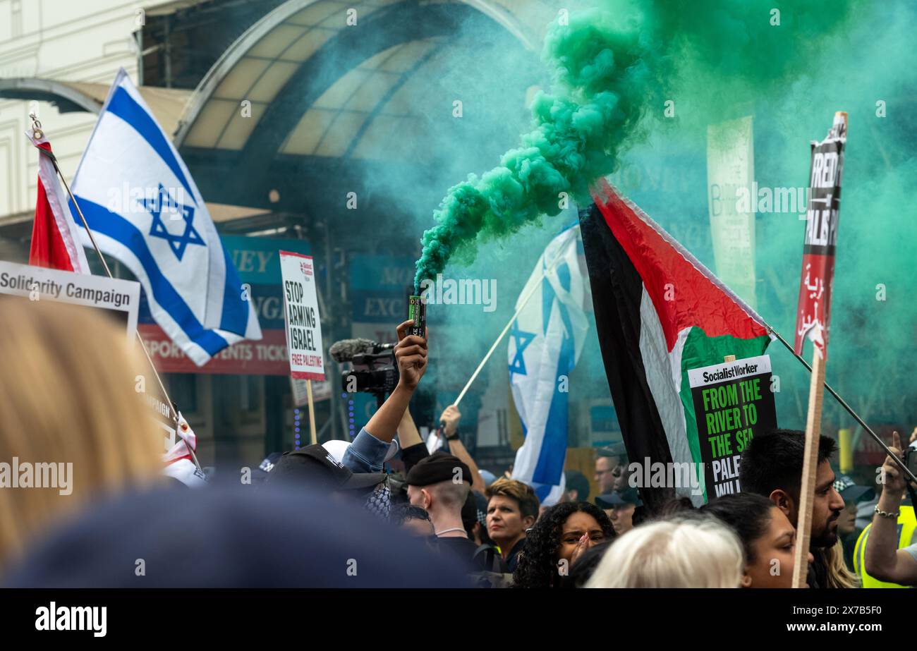 London, Großbritannien. 18. Mai 2024: Ein pro-palästinensischer Demonstrant hält ein grünes Licht, als der Nakba-Marsch 76 für Palästina gegen israelische Angriffe auf Gaza an den pro-israelischen Gegendemonstratoren im Piccadilly Circus im Zentrum Londons vorbeigeht. Ein gewaltiger marsch markiert den 76. Jahrestag der "palästinensischen Katastrophe" im Jahr 1948 und rief zu einem Waffenstillstand in Gaza auf. Stockfoto