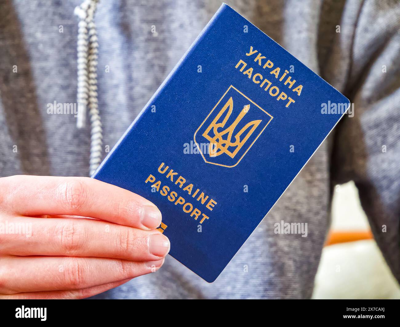 Blauer Pass mit goldenem Emblem, der die ukrainische Identität und globale Mobilität repräsentiert. Stockfoto