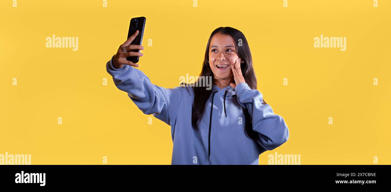 Lebensstil: Junge Latina Mädchen auf gelbem Hintergrund macht Videoanrufe Stockfoto