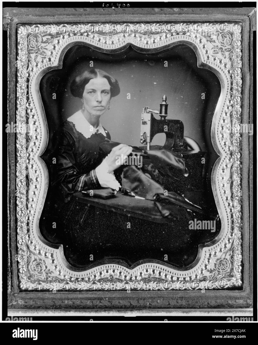Berufsbildnis einer Frau, die an einer Nähmaschine arbeitet, Seamstress., Bildunterschrift aus der Ausstellung 'American Treasures Memory': Tools of the Trade. Louis-Jacques-Mandé Daguerre erfand das Daguerreotypverfahren, das später in Frankreich am 19. August 1839 angekündigt wurde. Obwohl es sich um einen komplexen und langsamen Prozess handelte, nutzten amerikanische Fotografen diese neue Erfindung schnell, weil sie in der Lage waren, ein „wahrhaftiges Bild“ zu erfassen. In der Regel wurden Prominente, politische Persönlichkeiten und Handwerker oft eingeladen und ermutigt, ihre Bilder von Daguerreotyp machen zu lassen Stockfoto