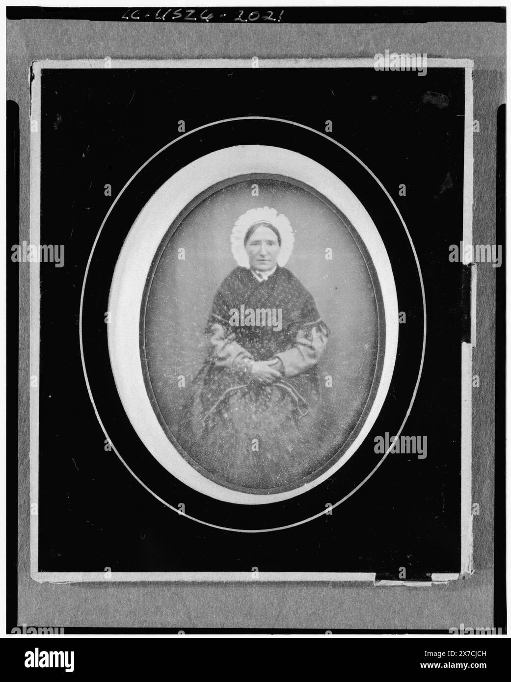 Nicht identifizierte Frau, Porträt dreiviertel Länge, nach vorne gerichtet, sitzend, in Passepartout-Matte, Etikett auf der Rückseite des Rahmens: 'Portraits au daguerreotype sur Papier et sur plaque de la maison eu en Clement, Rue de Rivoli 29, Pres la Place du ... au coin de la rue ... Pygmalion'. Zeigt ein Porträt von Daguerre und eine daguerrische Kamera, Objektiv und gerahmtes Foto. Geschrieben auf der Rückseite des Rahmens: 2194., Geschenk; Charles W. Millard; 1976; (DLC/PP-1976:096). ist Teil von : Sammlung von Daguerreotypen , . Stockfoto