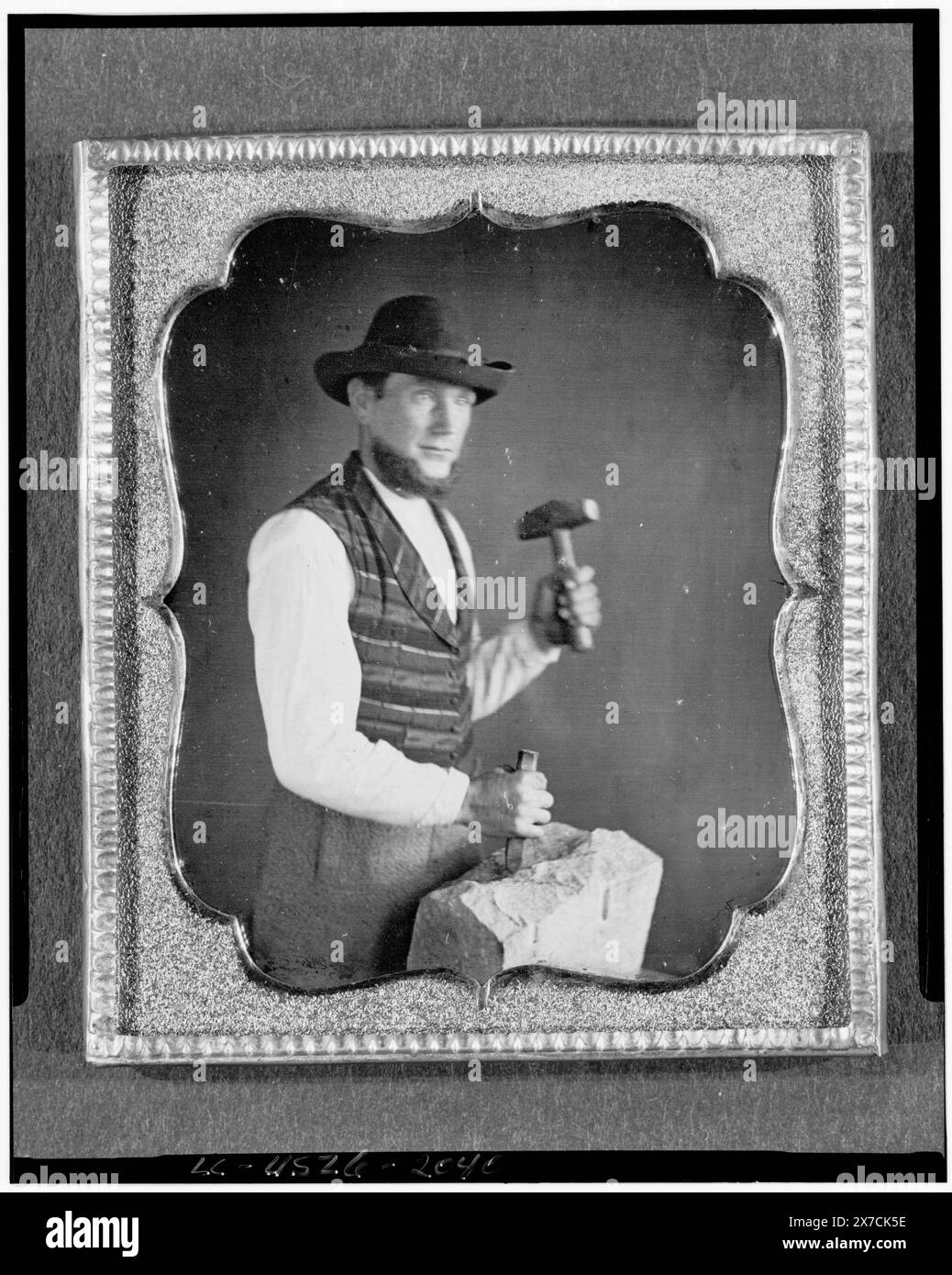 Berufsbildnis eines nicht identifizierten Steinmetzers, dreiviertel lang, dreiviertel rechts, Hammer und Meißel gegen einen Steinblock hält, Bildunterschrift aus der Ausstellung „American Treasures Memory“: Tools of the Trade. Louis-Jacques-Mandé Daguerre erfand das Daguerreotypverfahren, das später in Frankreich am 19. August 1839 angekündigt wurde. Obwohl es sich um einen komplexen und langsamen Prozess handelte, nutzten amerikanische Fotografen diese neue Erfindung schnell, weil sie in der Lage waren, ein „wahrhaftiges Bild“ zu erfassen. Typischerweise Porträts in der Natur, Berühmtheiten, politischen Persönlichkeiten und Handwerkern Stockfoto