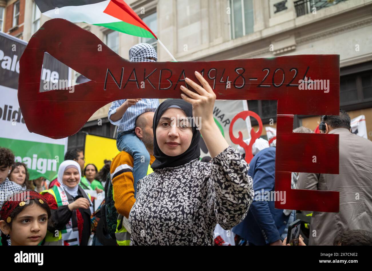 London, Großbritannien. 18. Mai 2024: Eine Frau in traditioneller palästinensischer Kleidung hält einen „palästinensischen Schlüssel“ beim Nakba-Marsch 76 für Palästina gegen ISR Stockfoto