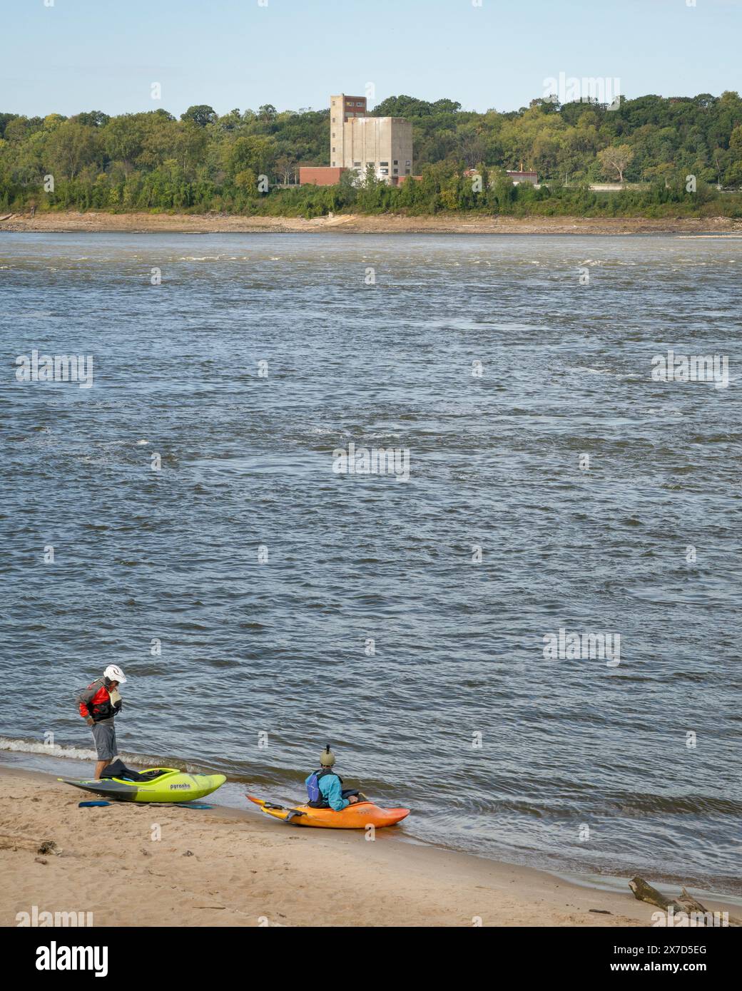 Granite City, Il, USA – 8. Oktober 2023: Zwei Kajakfahrer starten Wildwasserkajaks von einem Strand am Mississippi River unterhalb eines Wassers des Low W Stockfoto