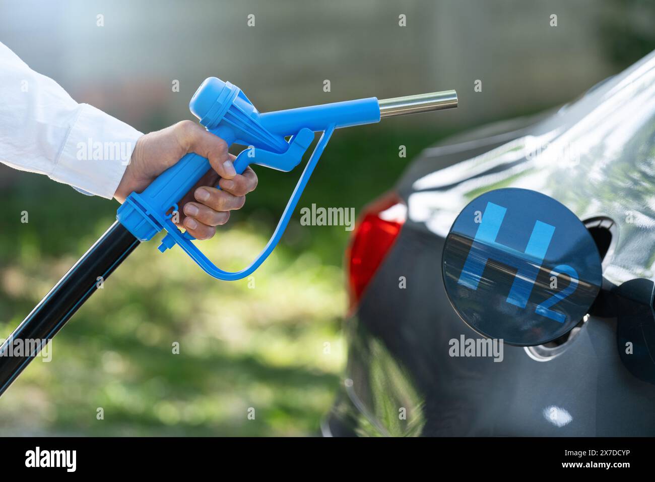Der Mann hält eine Wasserstoffdüse. Betanken des Autos mit Wasserstoffkraftstoff. Konzept... Stockfoto