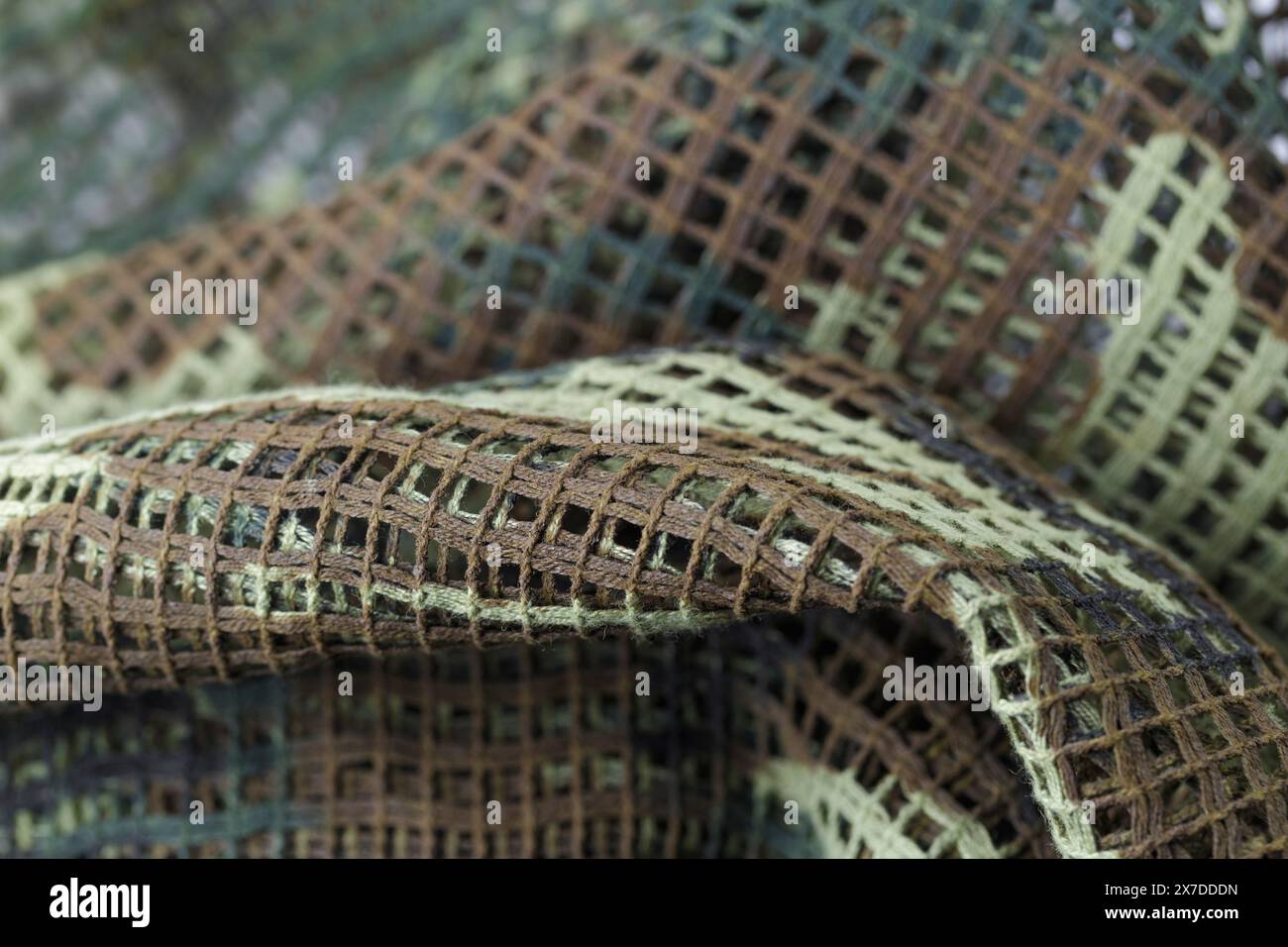 Ein Stück Camouflage-Stoff mit einem grünen und braunen Muster. Das Gewebe besteht aus einem Netzmaterial und hat eine raue Textur Stockfoto