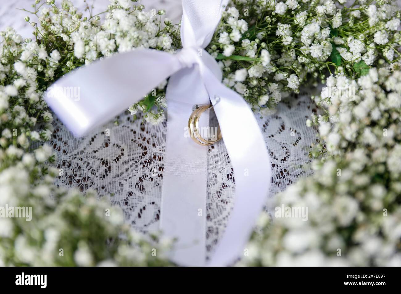 Eheringe mit weißer Schleife in Blumenanordnung - selektiver Fokus Stockfoto