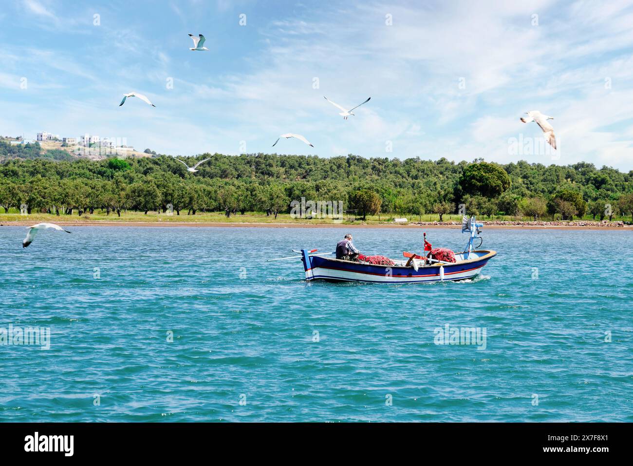 Türkischer Fischer, der die Fischernetze auf dem Boot über dem Meer in Ayvalık, Türkei, vorbereitet. Stockfoto