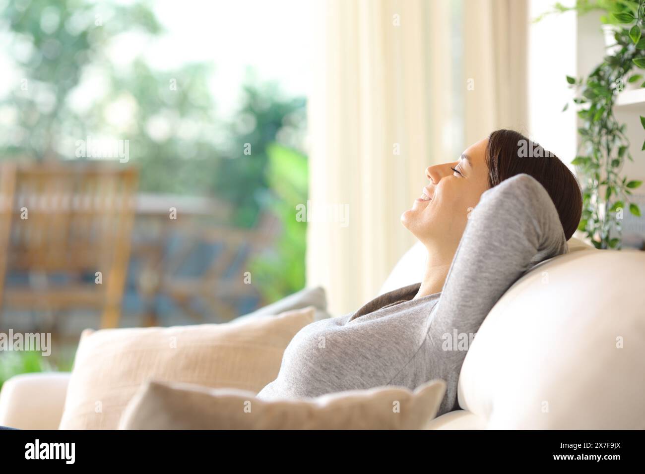 Profil einer glücklichen Frau, die zu Hause auf einer Couch ruht Stockfoto