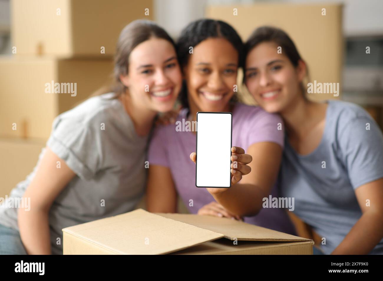 Baum glückliche Multi-ethnische Frauen zeigen leeren Telefonbildschirm und ziehen Haus Stockfoto