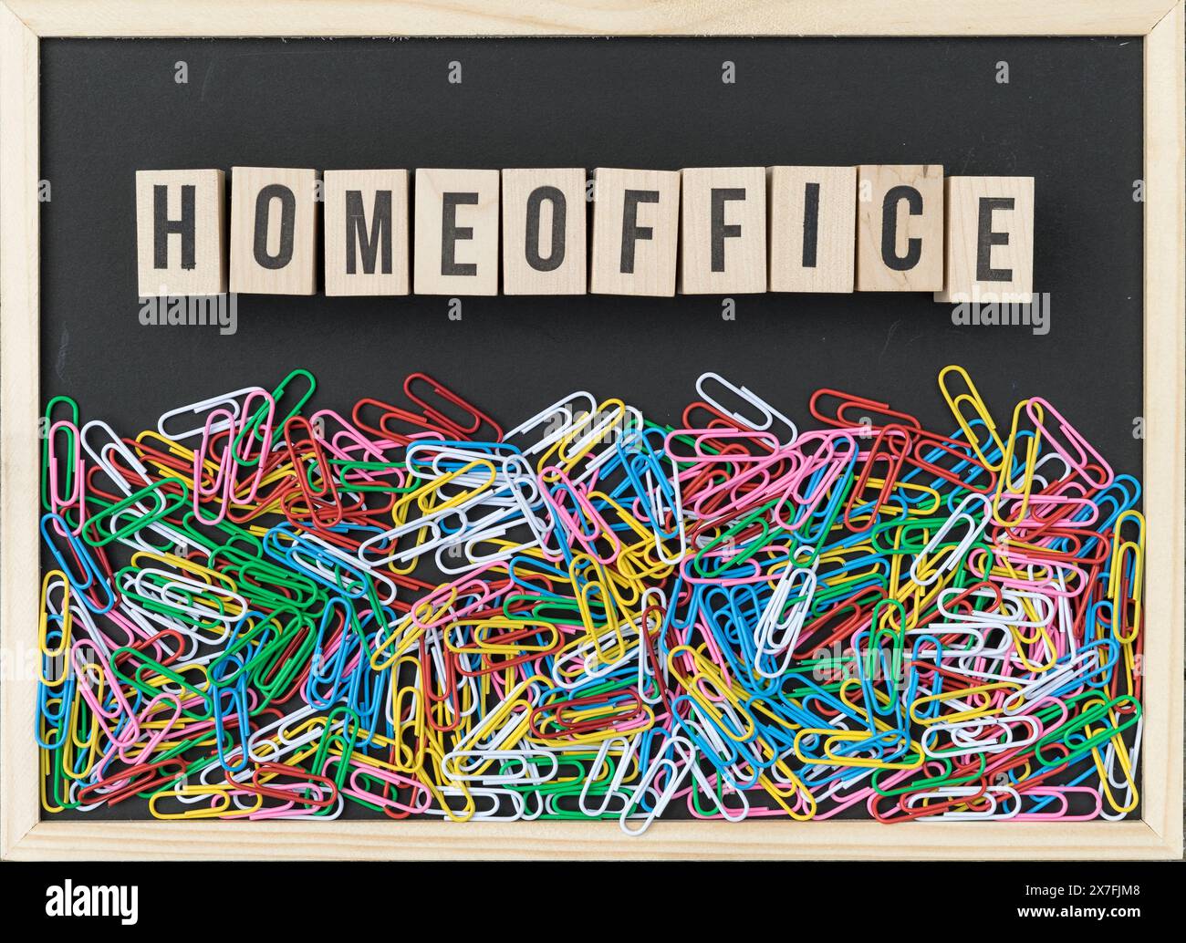 Schwarzer Hintergrund mit bunten Büroklammern und Holzwürfeln mit dem Text: HomeOffice Stockfoto