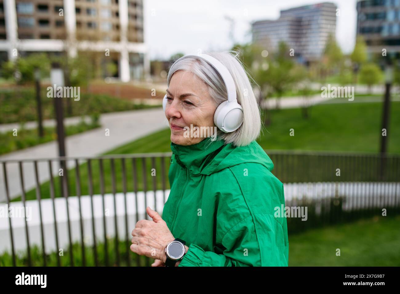 Reife Frau, die Musik hört, während sie läuft. Sport nach der Arbeit für gute psychische Gesundheit, körperliche Gesundheit, Stressabbau und Stimmung. Stockfoto