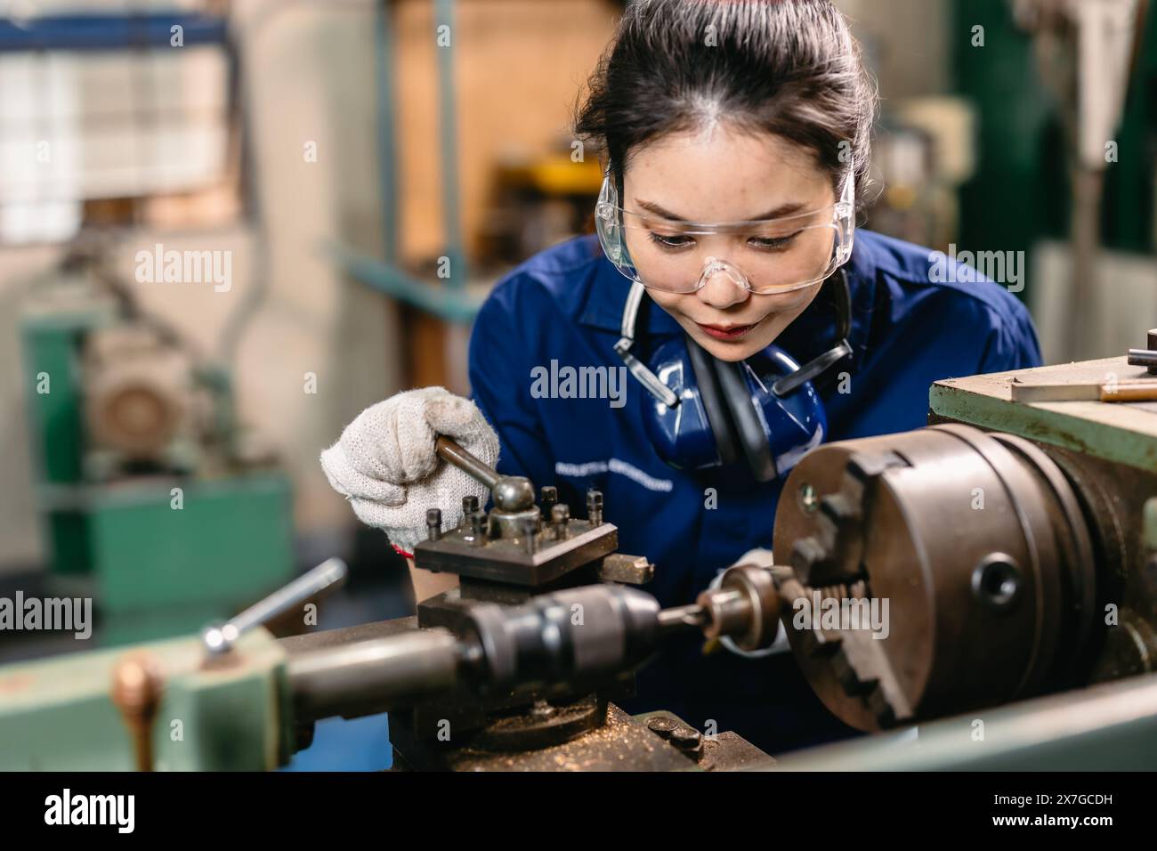 Professioneller Ingenieur Arbeiter mit Sicherheitsaugenschutz Fokus, der in Metalldrehmaschine Fräsmaschine Schwerindustriefabrik arbeitet. Stockfoto