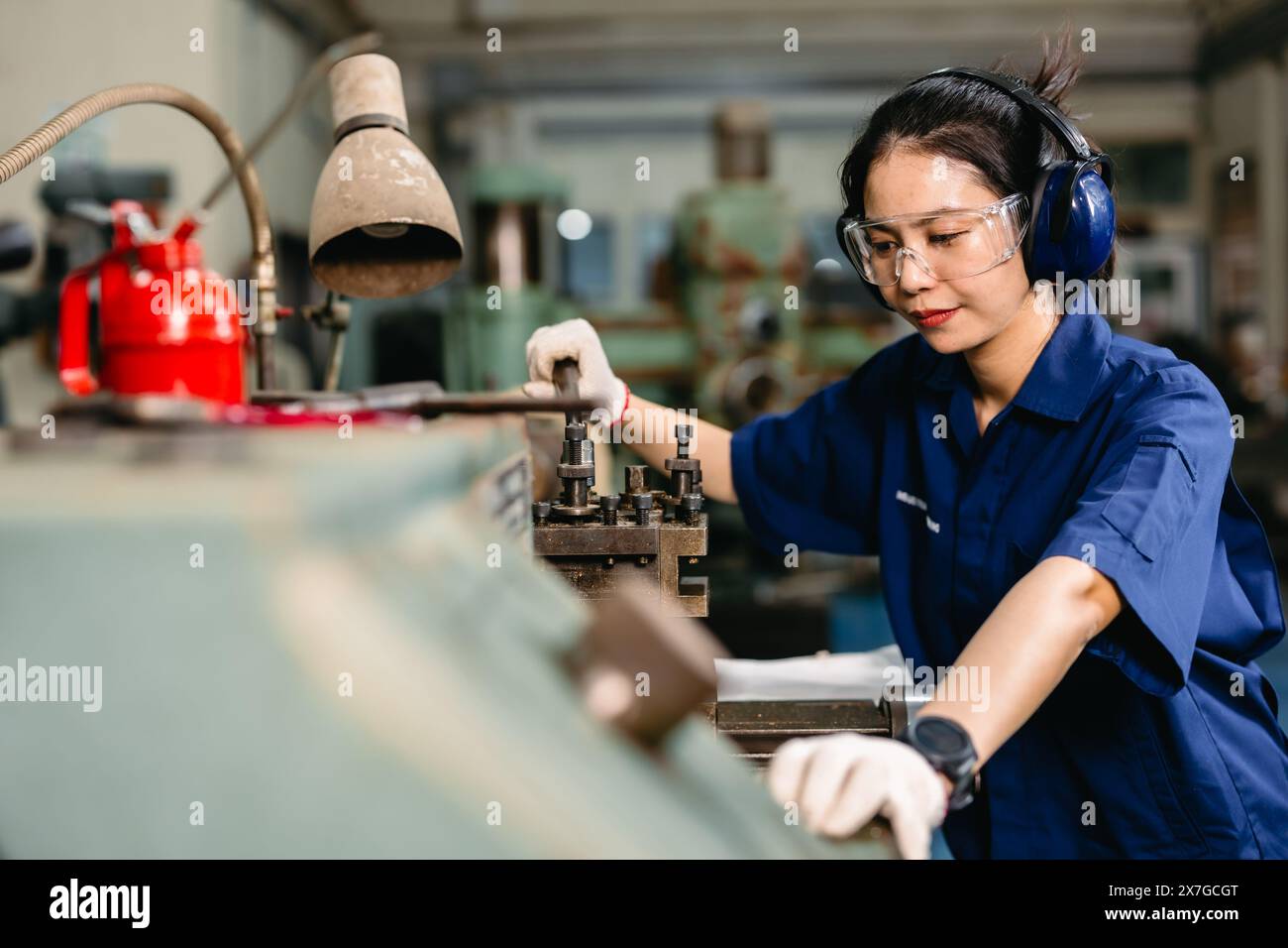 Professioneller Ingenieur Arbeiter mit Sicherheitsaugenschutz Fokus, der in Metalldrehmaschine Fräsmaschine Schwerindustriefabrik arbeitet. Stockfoto