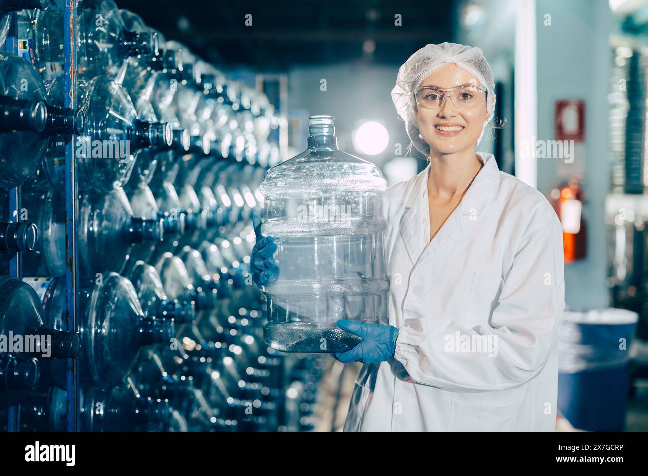 Junge kaukasische Arbeitnehmerinnen arbeiten in Trinkwasserfabrik Zählen Wasserflasche Gallonen-Vorrat an hygienisch einheitlichem Arbeitsplatz Stockfoto