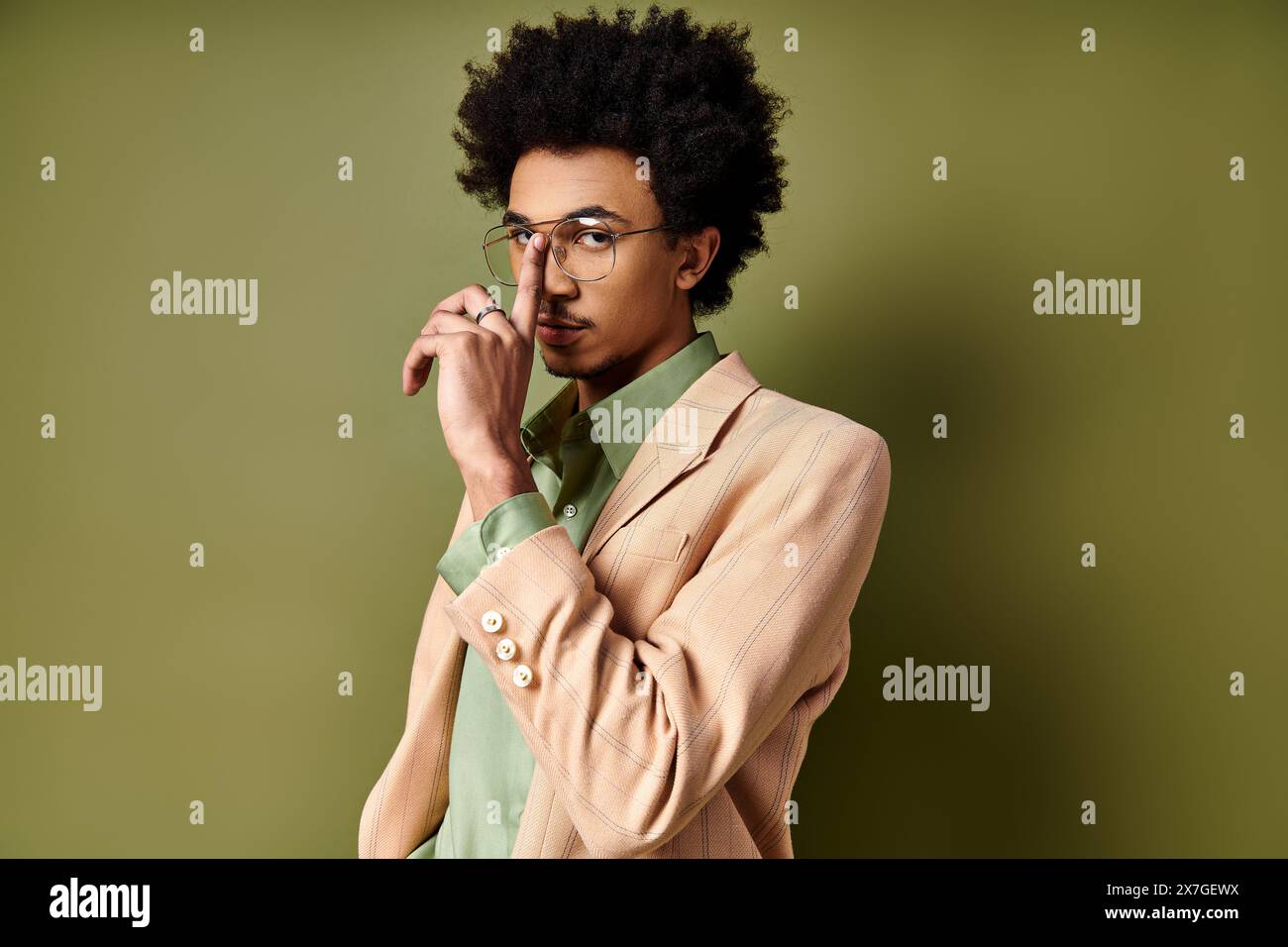 Stilvoller junger afroamerikanischer Mann in trendiger Kleidung und Brille auf grünem Hintergrund. Stockfoto