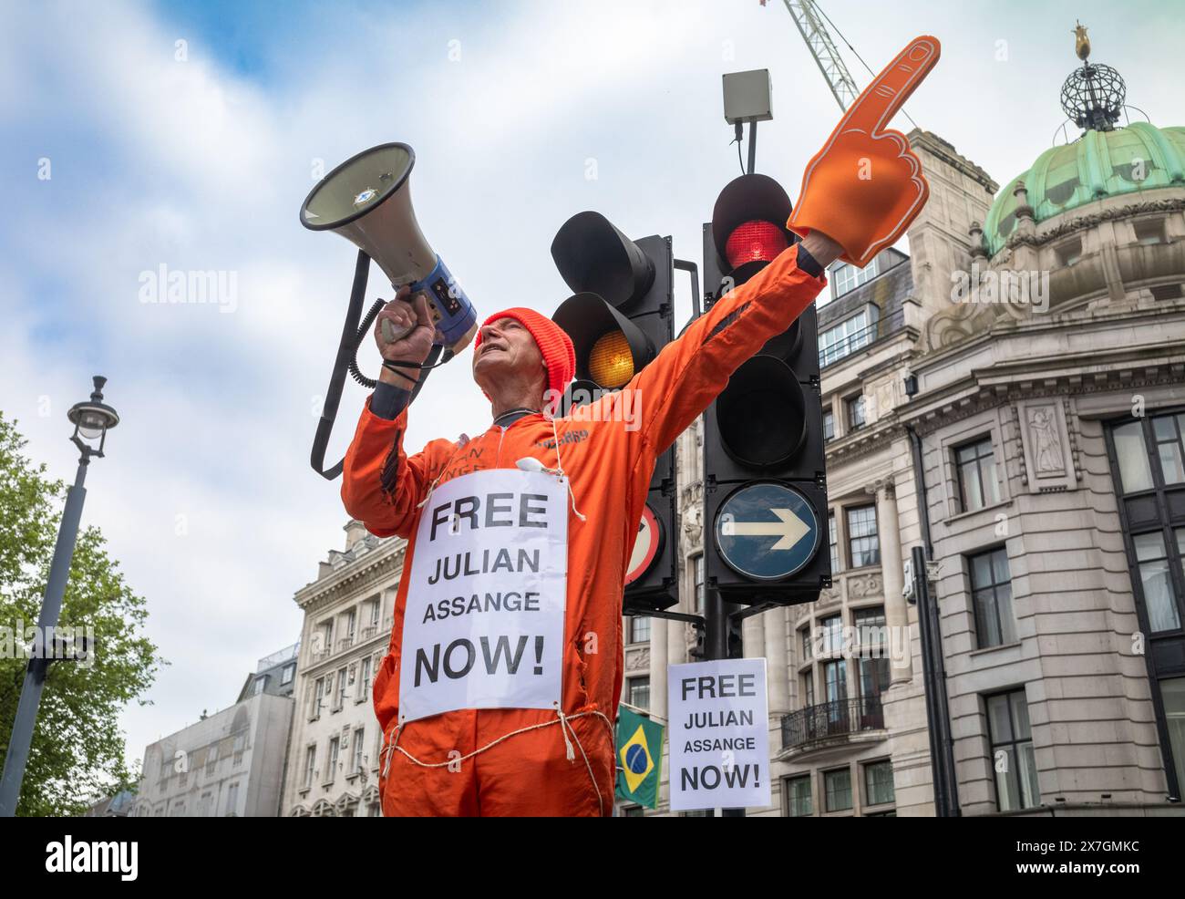 Ein Demonstrant in einem orangefarbenen Kesselanzug hält ein Megaphon, als er die Freilassung des Wikileaks-Gründers Julian Assange aus dem Gefängnis fordert. Stockfoto