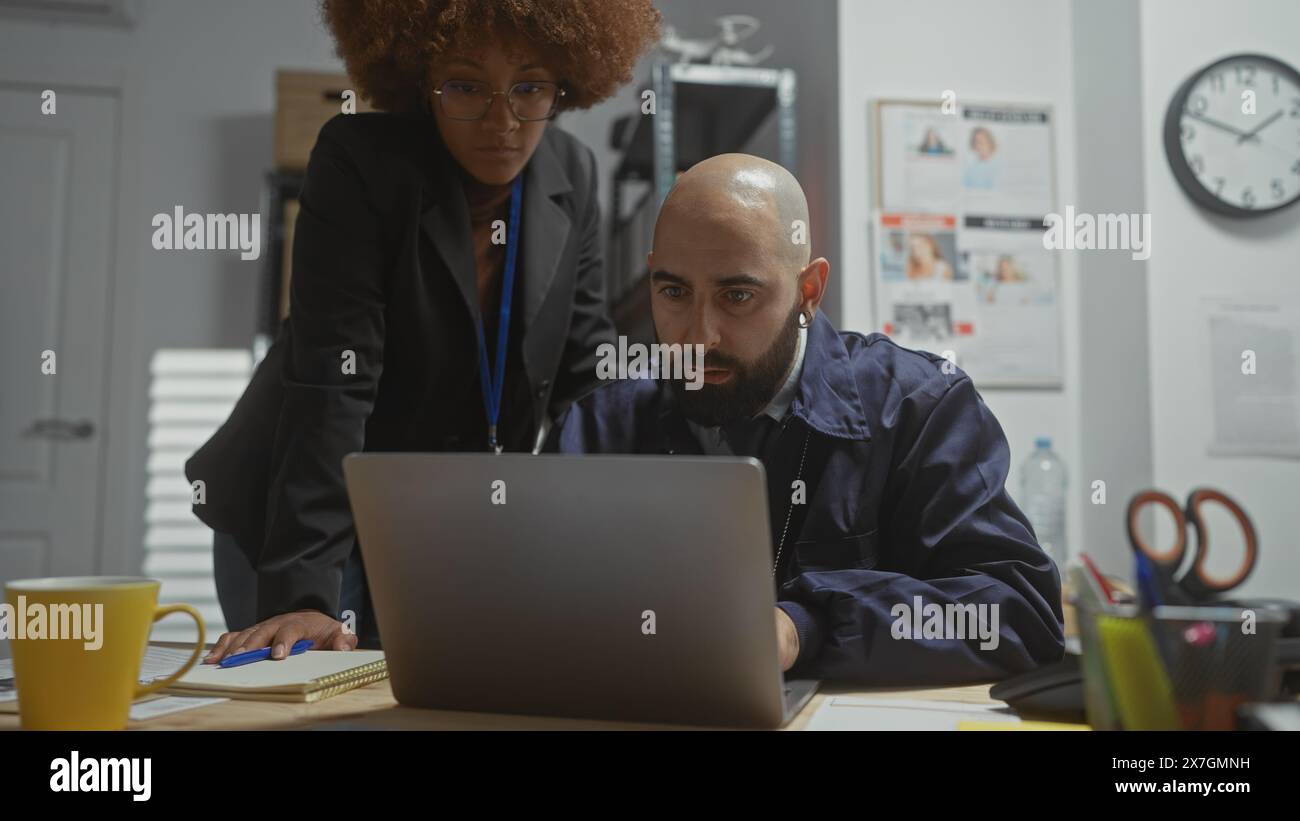 Mann und Frau in Zivil arbeiten zusammen an einem überfüllten Schreibtisch und deuten auf verdeckte Detektive oder Überwachungsarbeiten in einem Büro an. Stockfoto