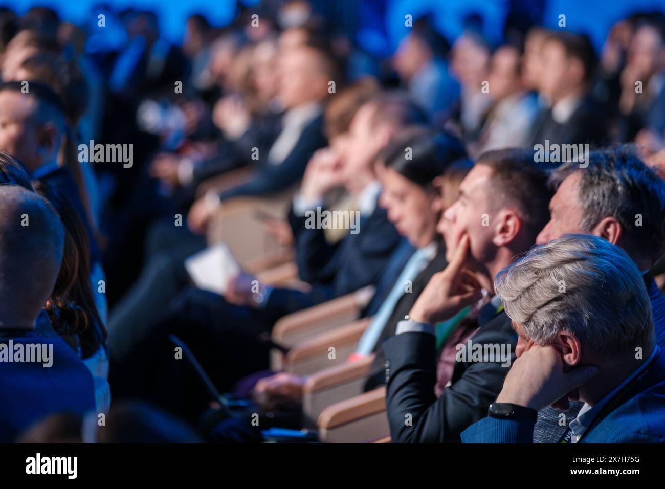 Verschwommenes Bild des sitzenden Publikums, das während einer Geschäftskonferenz aufmerksam zuhört, wodurch Fokus und Engagement hervorgehoben werden. Stockfoto
