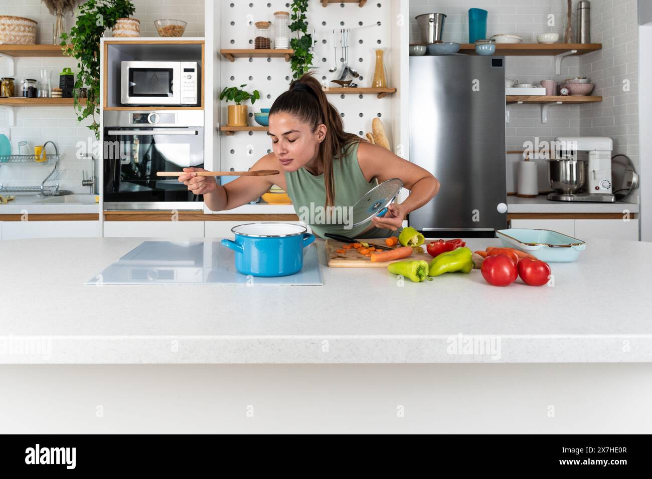 Junge sportliche Frau, die während der Menstruationszeit eine Gesundheitsmahlzeit vorbereitet. Frau kocht Gemüse in der Hausküche, während sie Menstruation hat. Gesundheit Stockfoto