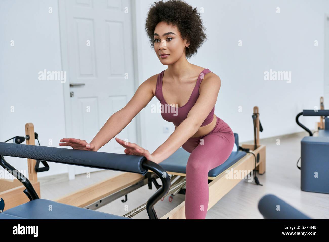 Frau in rosa Oberteil und Leggings, die anmutig trainiert. Stockfoto