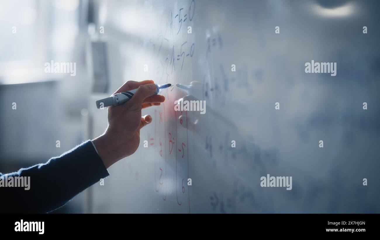 Makroaufnahme eines blauen Markierstifts, der mit einer Hand gehalten wird. Lehrer schreibt Gleichungen auf einem Whiteboard mit mathematischen Formeln. Hochschulbildung an der Technischen Universität Konzept. Stockfoto