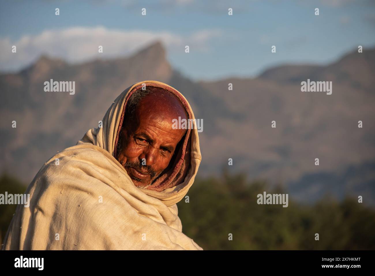 Porträt eines traditionell gekleideten Äthiopiers, in abgelegenem Dorf auf dem Land, mit wunderschönem Blick auf die mächtige Berglandschaft im Hintergrund Stockfoto