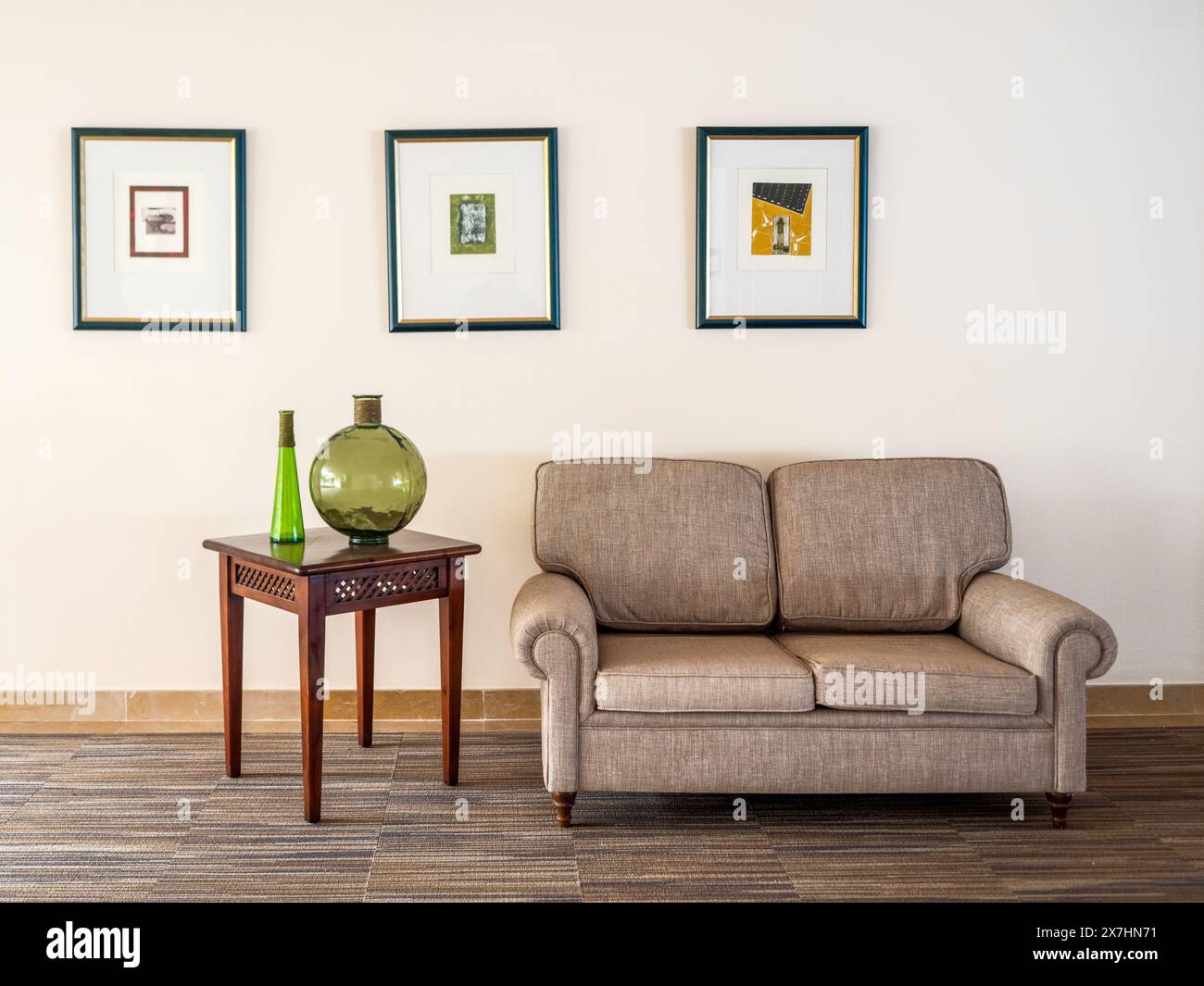 Wohnbereich im Innendesign mit Sofa, weichen Möbeln, Tisch, Gläsern und Wandbildern Stockfoto