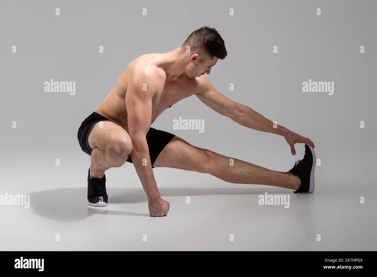 FIT Young man Stretching vor dem Workout auf minimalistischem Hintergrund Stockfoto