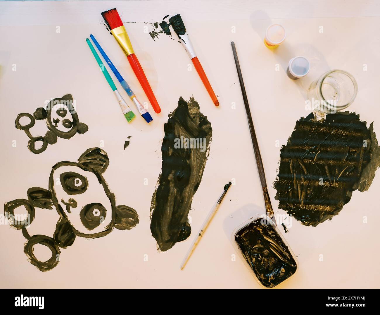 Zwei Pandabären auf weißem Blatt, neben Pinseln und Farbgläsern Stockfoto