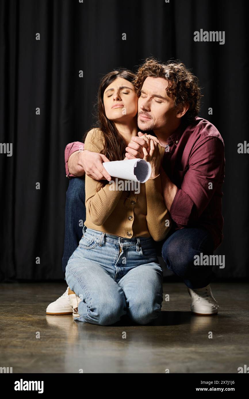 Ein hübscher Mann und eine schöne Frau saßen auf dem Boden, eingetaucht in eine Theaterprobe. Stockfoto Ein hübscher Mann und eine schöne Frau saßen auf dem Boden, eingetaucht in eine Theaterprobe. Stockfoto