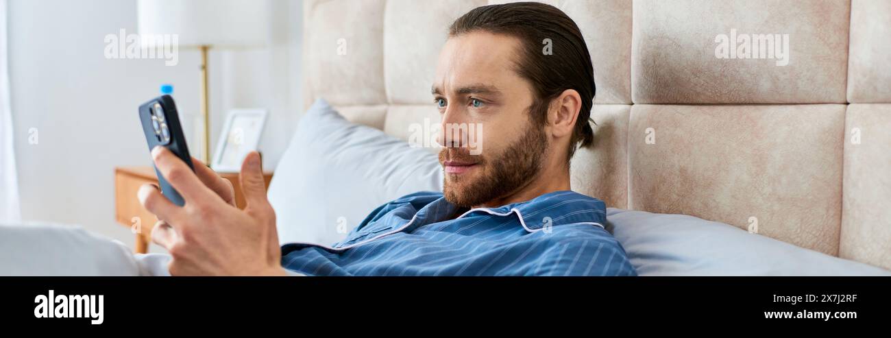 Ein Mann, der sich im Bett entspannt und Achtsamkeit mit seinem Handy in der Hand übt. Stockfoto