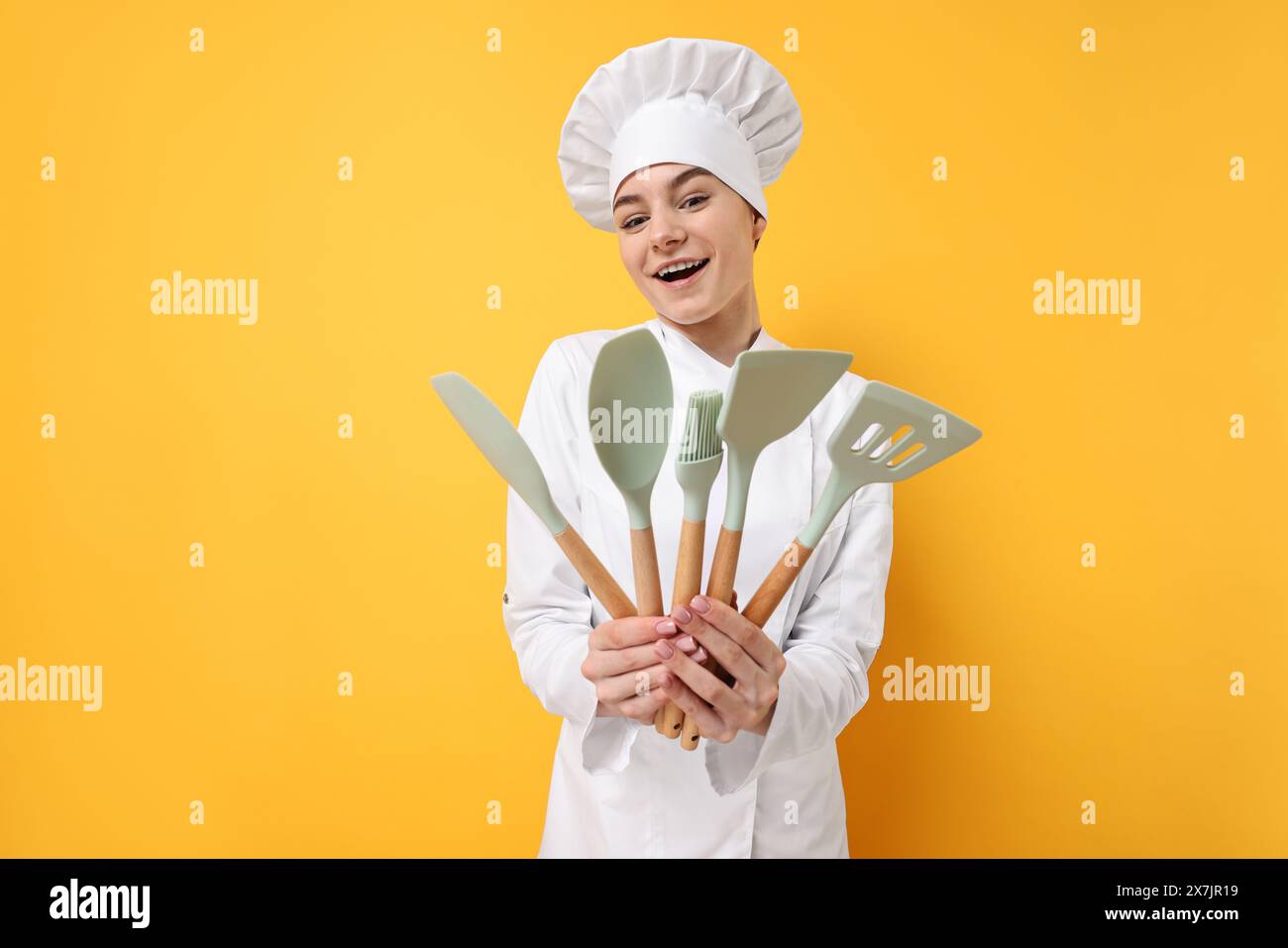 Professioneller Koch mit Küchenutensilien auf gelbem Hintergrund Stockfoto