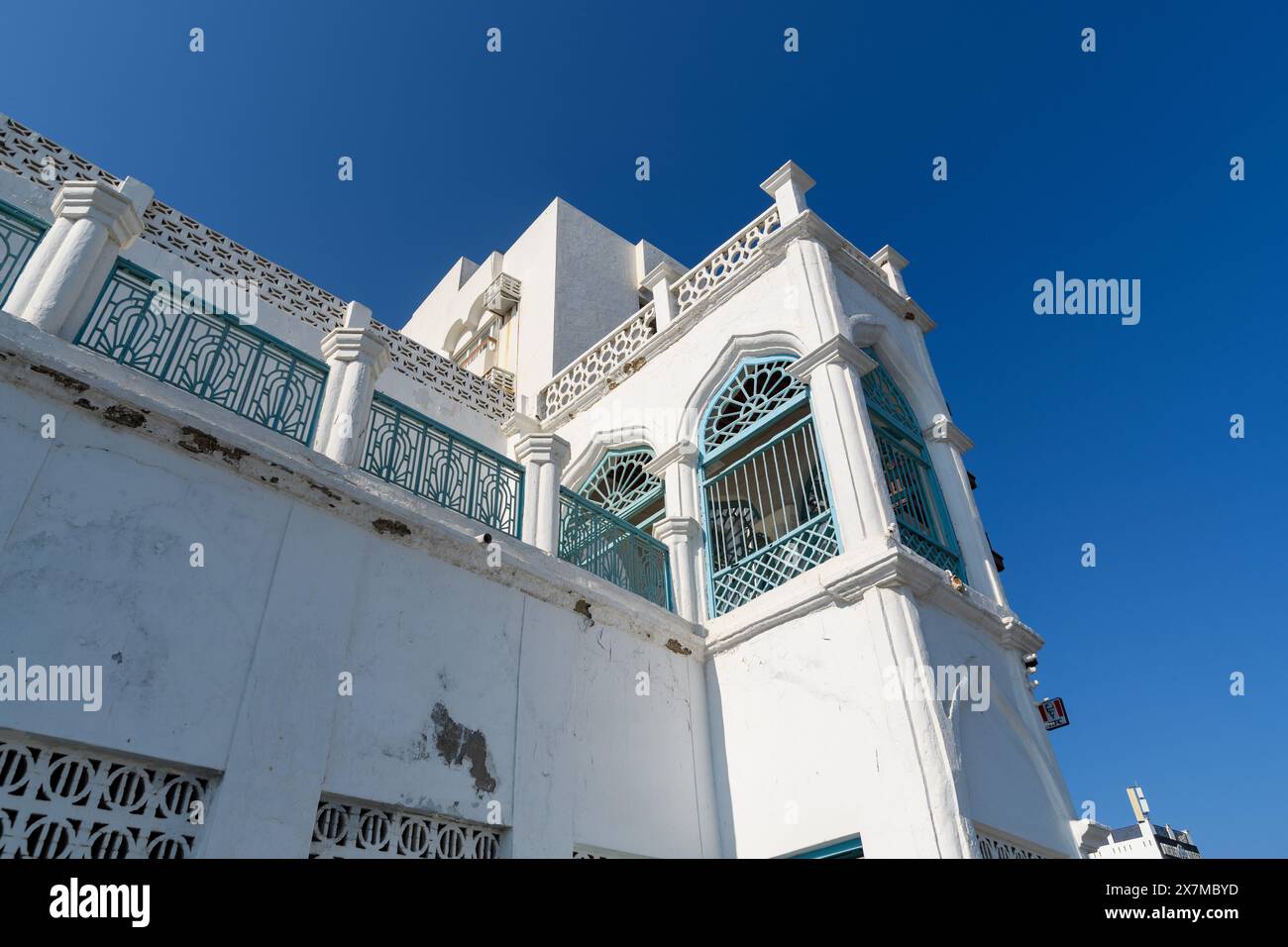 Muscat, Oman - 2. Januar 2024: Die komplizierte Schönheit der omanischen Architektur mit weißen Wänden und grünen Akzenten unter klarem Himmel. Stockfoto