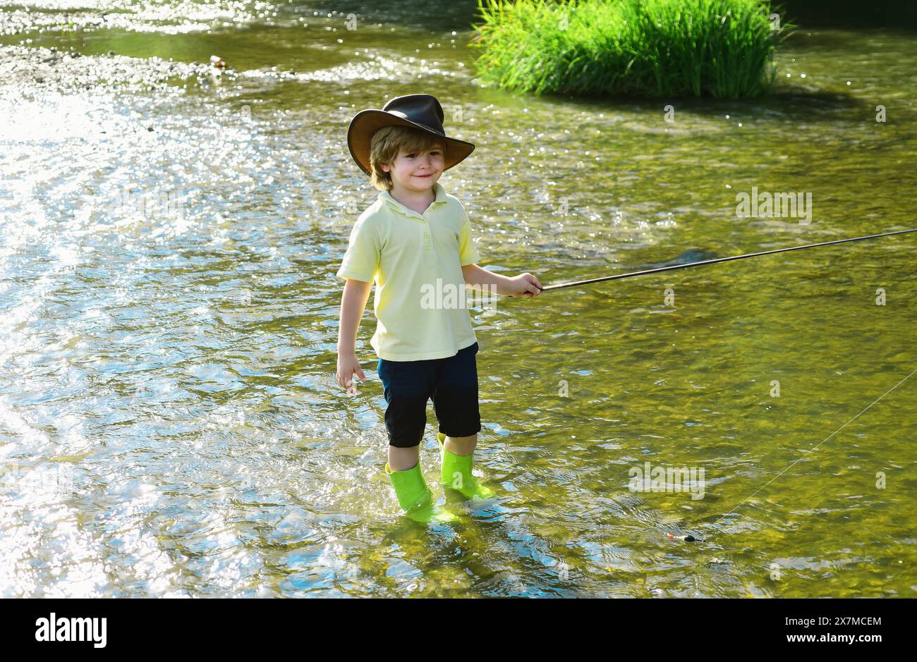 Süßer kleiner Junge, der auf dem Teich angelt. Junger Mann