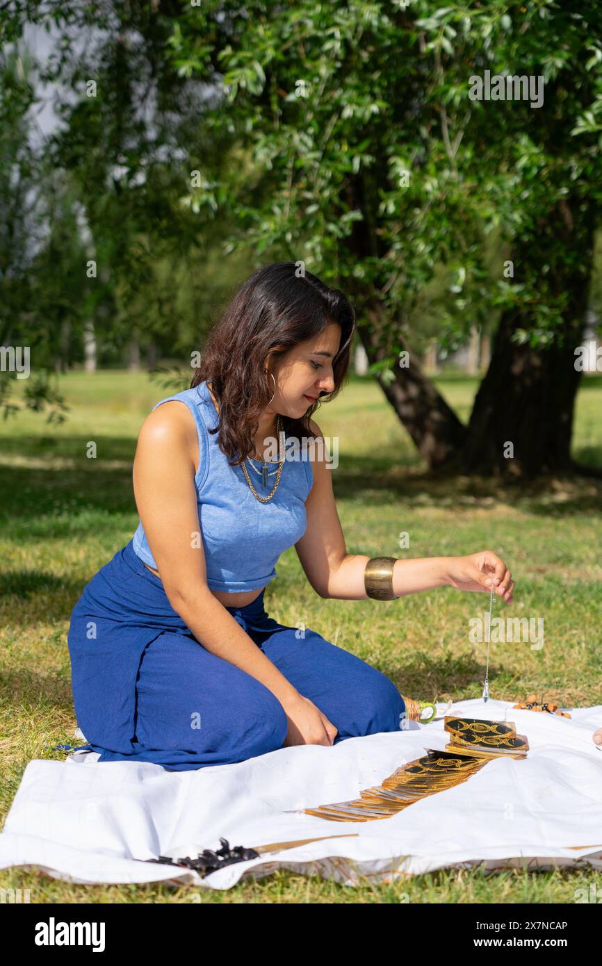 Lateinische Frau liest Tarotkarten mit einem Pendel Stockfoto