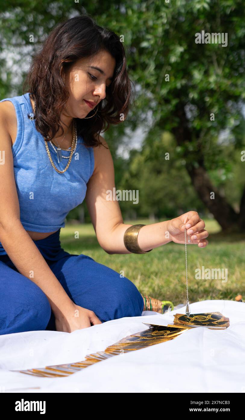 Kolumbianische Frau liest Tarotkarten mit einem Pendel Stockfoto