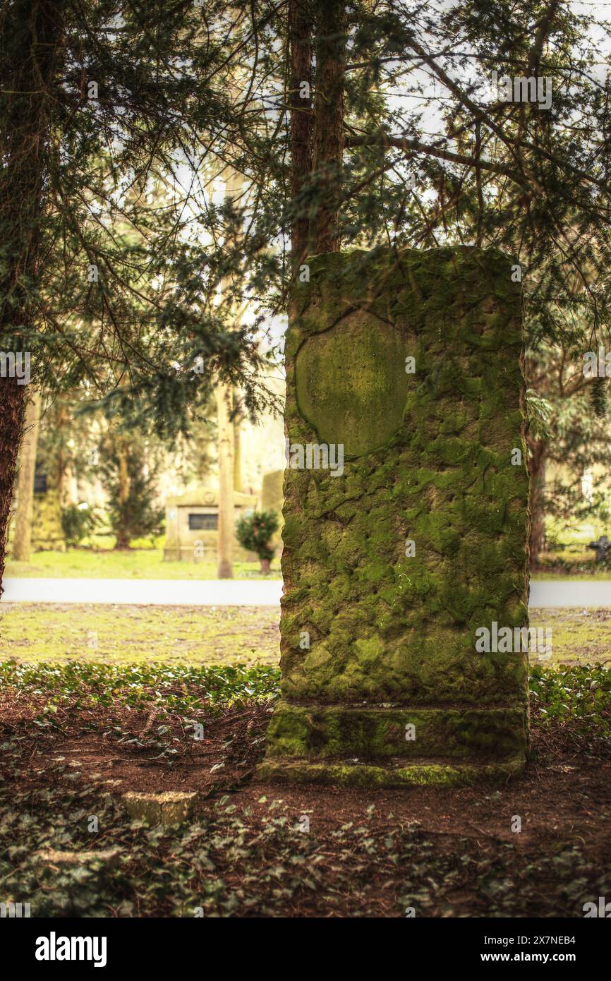 Ein riesiger bemooster Grabstein auf einem Friedhof in Deutschland. Stockfoto