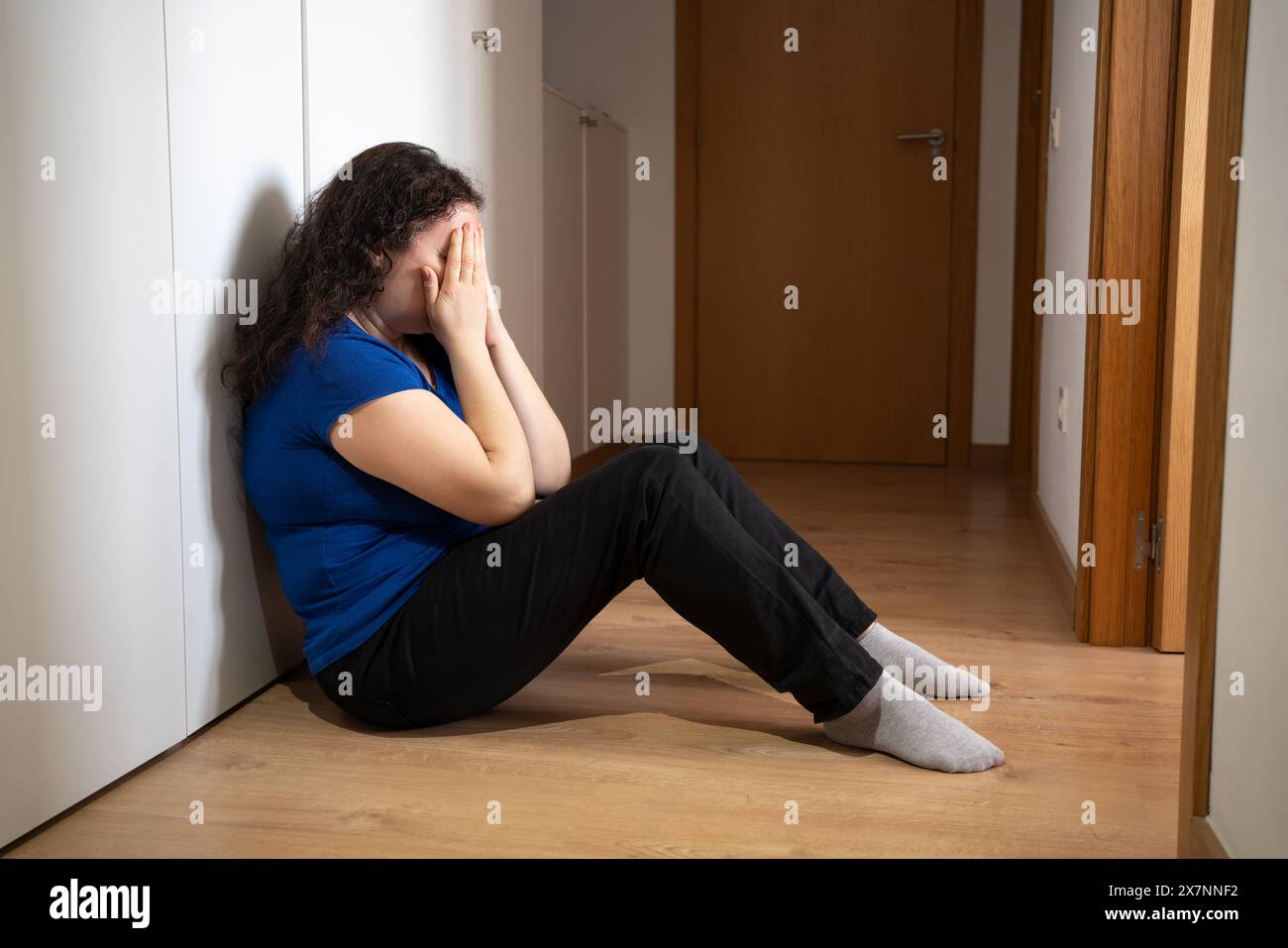 Verärgerte Problemfrau mit Kopf in den Händen sitzend auf dem Boden Konzept für Mobbing, Depressionen Stress oder Frustration am Arbeitsplatz Stockfoto