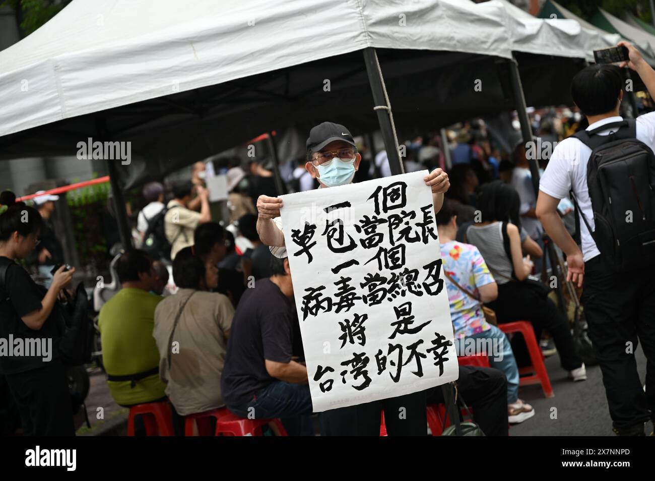 Taipeh, Taiwan. Mai 2024. Ein Mann hält ein Plakat mit der Aufschrift „einen inkompetenten Bungler als parlamentssprecher und einen Virus wie die KMT-Komitee-Peitsche zu haben, ist Taiwans Unglück“. Das taiwanesische parlament diskutiert derzeit mehrere umstrittene Gesetzesvorschläge der Opposition. Die Gegner der Initiativen befürchten einen Zerfall der Demokratie in Taiwan. Quelle: Johannes Neudecker/dpa/Alamy Live News Stockfoto