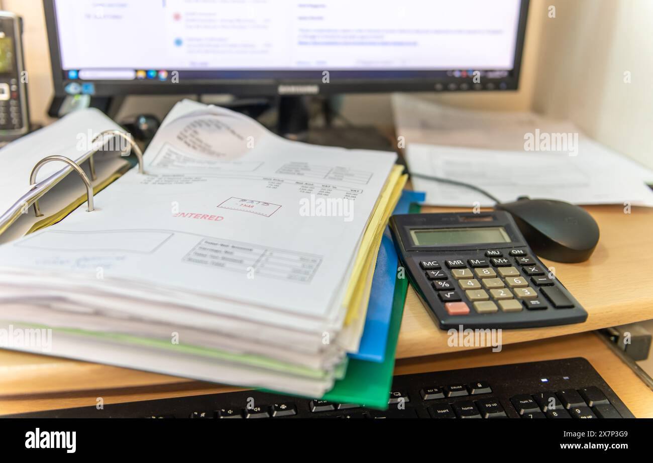 Ein Business-Arbeitsplatz mit einem Ordner mit Rechnungen, einem Tischcomputer, einer Tastatur, einer Maus und einem Taschenrechner. Unternehmensbuchhaltungskonzept. Stockfoto
