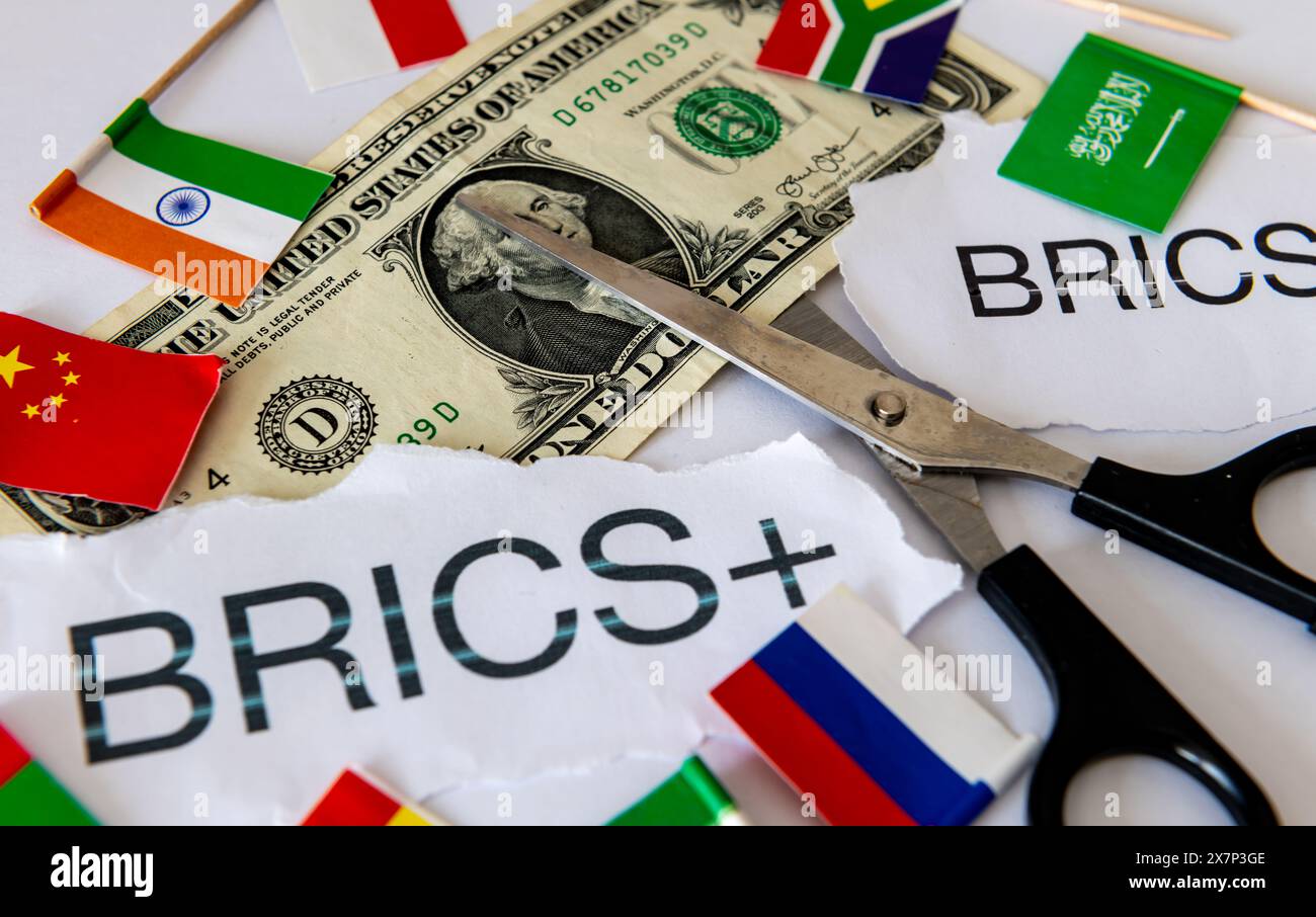 Ein Demoollarisierungskonzept mit den Worten und Länderflaggen des Blocks BRICS und BRICS+ Länder, einer Schere und einem US-Dollar-Schein. Stockfoto