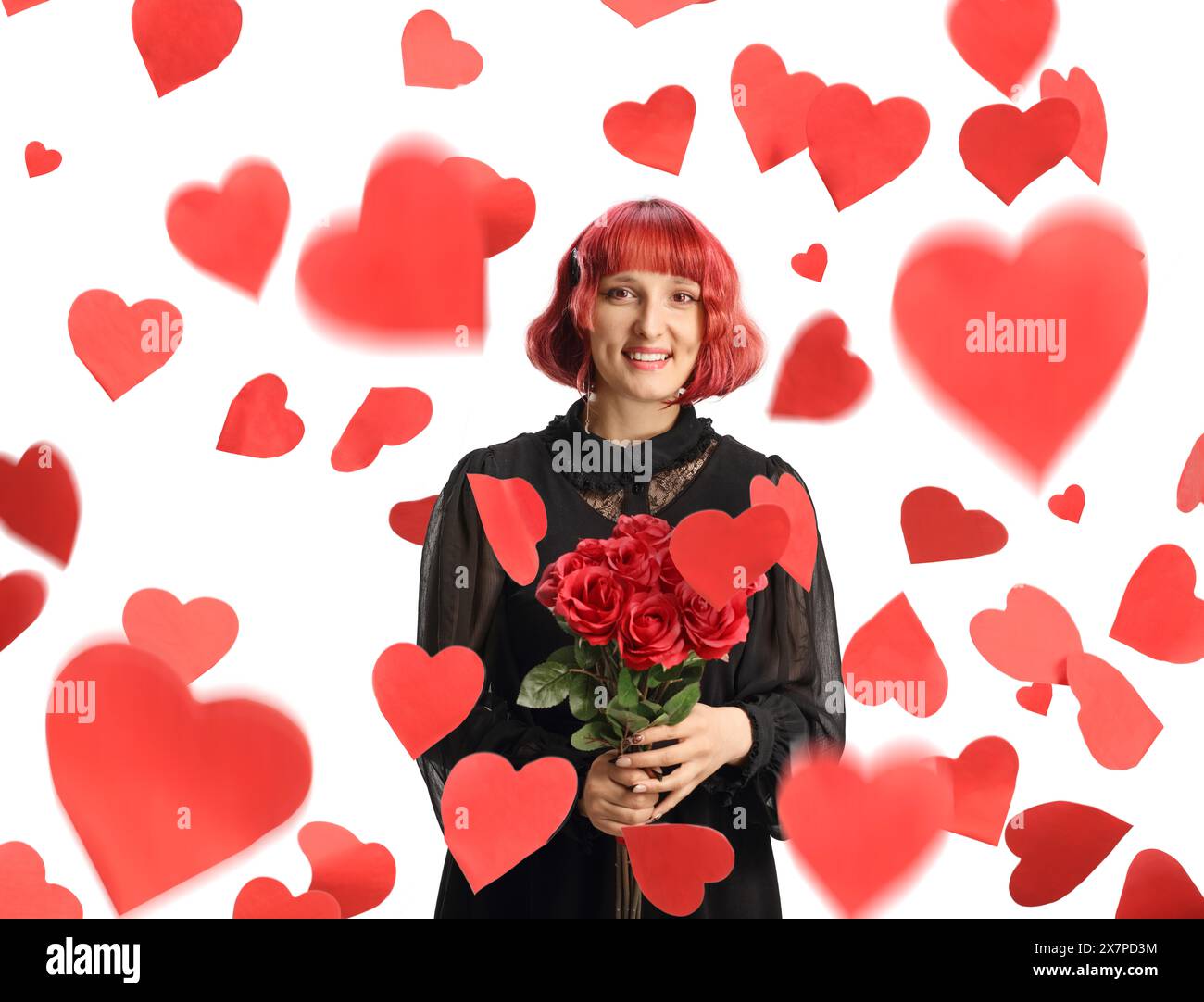 Eine junge Frau, die einen Haufen roter Rosen unter dem Regen von Herzen hält, isoliert auf weißem Hintergrund Stockfoto