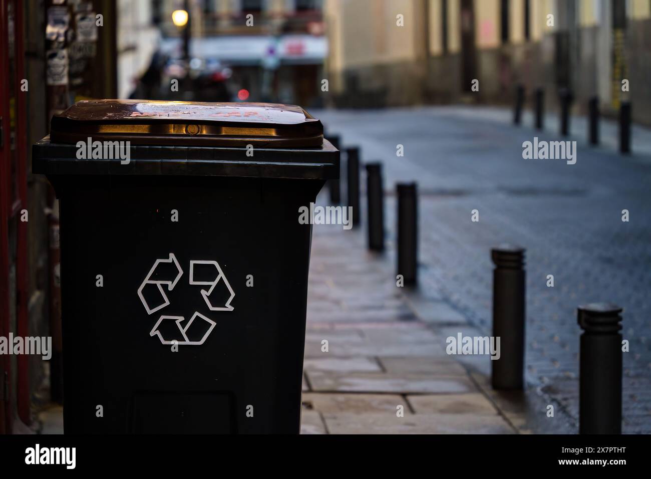 Schwarzer Mülleimer mit dem Recycling-Symbol am Straßenrand Stockfoto