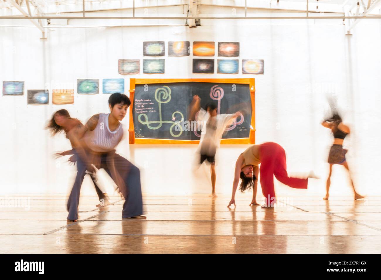 Verschwommene Figuren bewegen sich in einer temperamentvollen Tanzzeremonie und erwecken ein Gefühl ganzheitlicher Heilung und Gemeinschaft in einem lebendigen Workshop Stockfoto